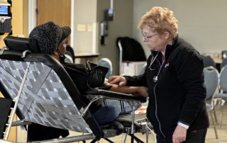 Nurse tending to woman donating blood.